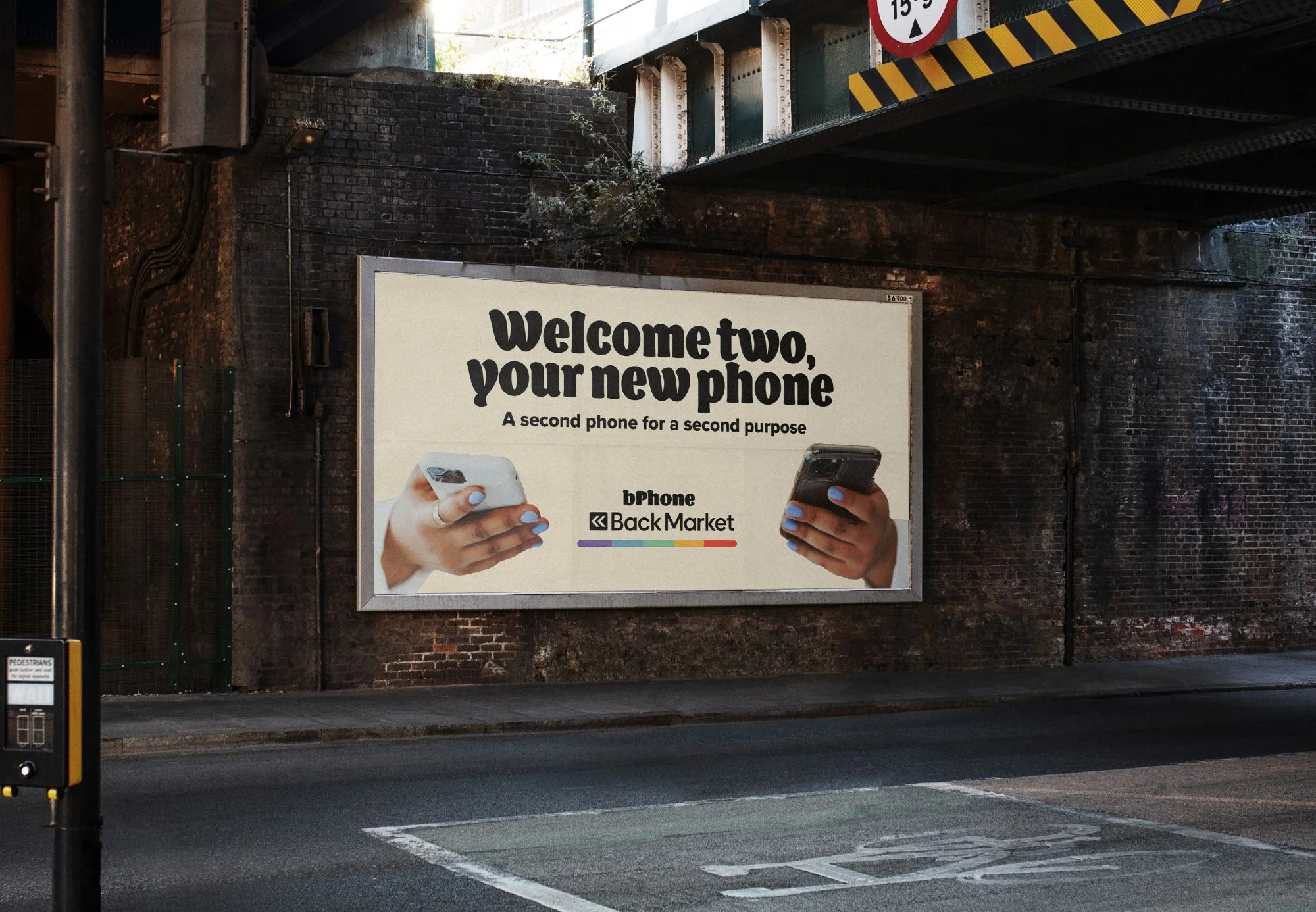 Billboard under a railway bridge: two hands, each holding a phone, 'Welcome two, your new phone'