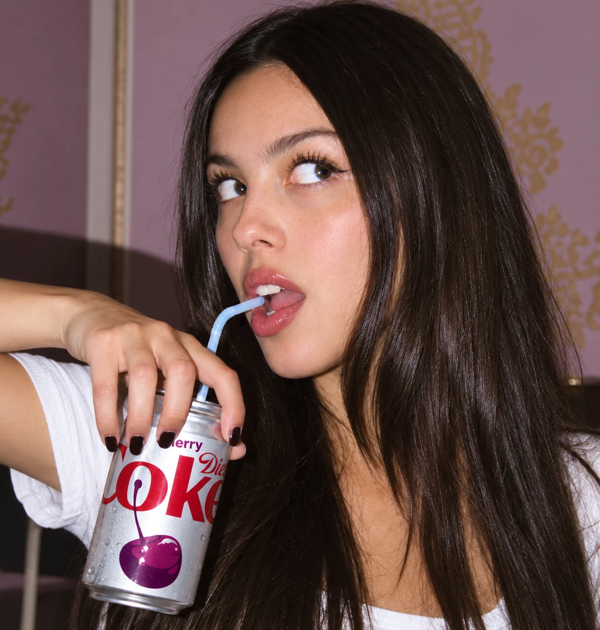 A woman drinks Diet Coke Cherry through a bendy straw, glancing sideways