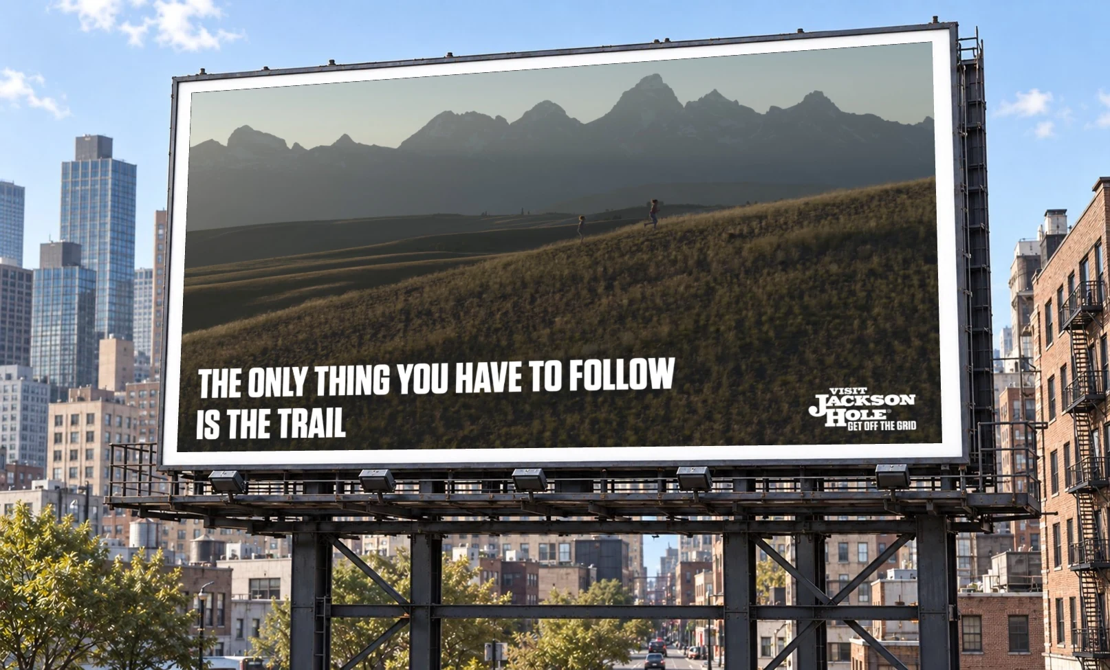 Billboard: 'The only thing you have to follow is the trail,' over two kids running a trail toward the Tetons