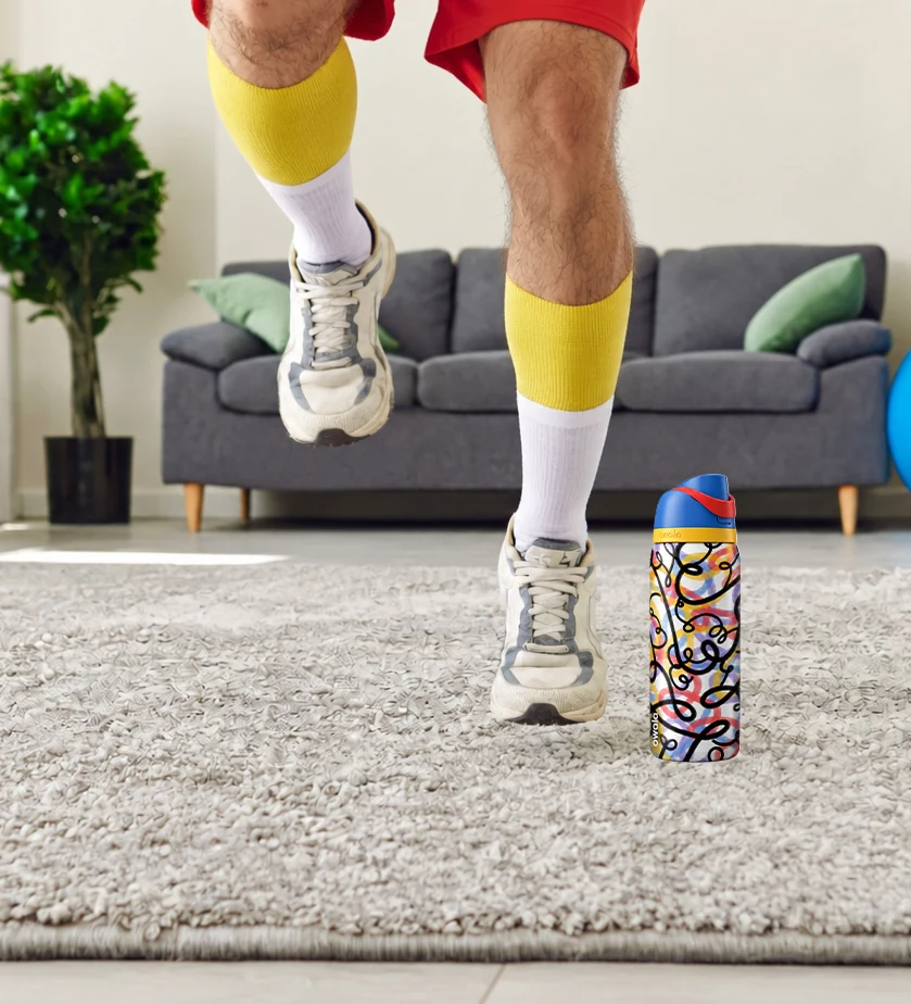 Working out: legs in yellow socks and sneakers jogging in place on a living-room rug next to an Owala