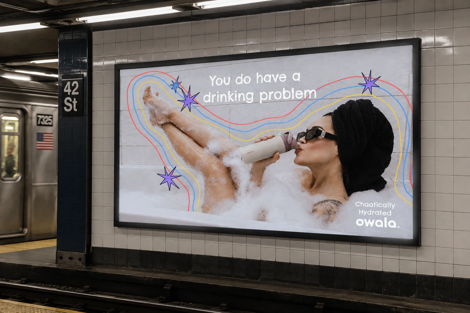 Subway platform billboard at 42 St: a woman in a bubble bath drinks from an Owala, 'You do have a drinking problem'